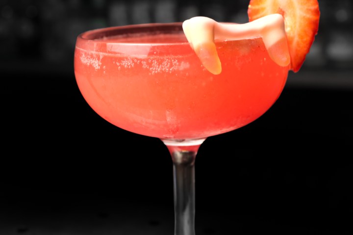 Halloween Special Red cocktail in a glass with a strawberry garnish
